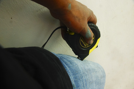 Hand Holding Measuring Tape Over White Backgroundの写真素材