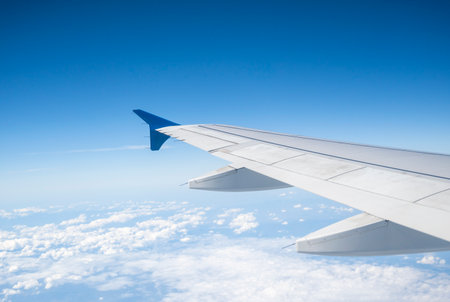 Aircraft Wing on beautiful blue sky and cloud background in altitude during flight. Wing of an airplane looking from the window.の写真素材