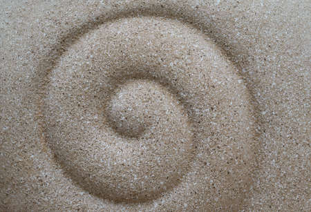 Abstract backgrounds of spiral design by hand on the white sand beach.の写真素材