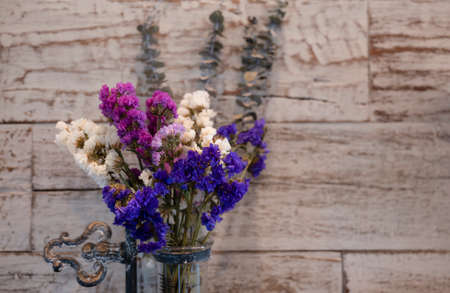 Bouquet of dried flowers in a glass vase on vintage wood background with copy space for text.