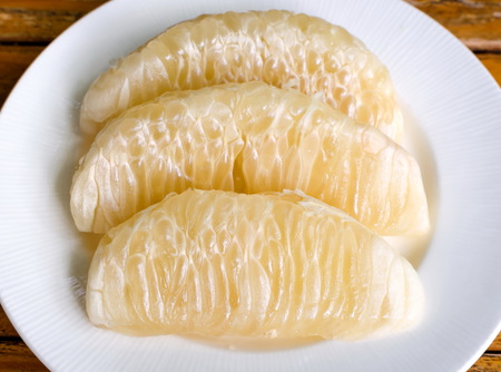 Thai pomelo fruit Peeled in white dish on wood table.の写真素材