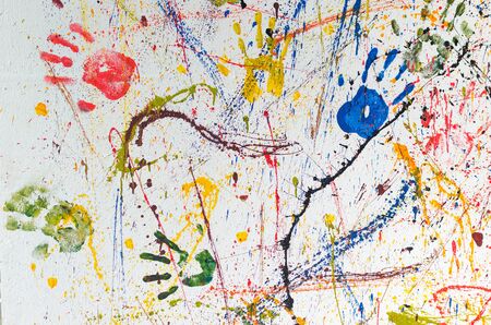 Multiple colorful children hand prints on white wall.