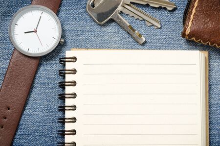 notebook  blank pages with watch and key on blue jeansの写真素材
