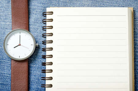watch and notebook with blank pages on blue jeansの写真素材