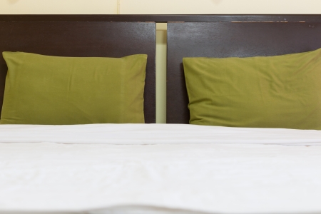Clean white bed and green pillowsの写真素材