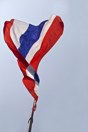 Thai or Thailand nation flag waving gently sway atop on blue sky background, AEC or ASEAN member flagの写真素材