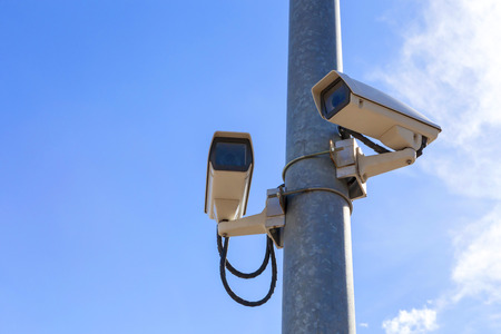 two cctv installed on the light pole, on blue sky background with copy space