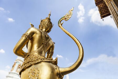 back view of a graceful golden kinaree image on blue sky background, Thai myth animal art at wat phra kaew, Bangkok, Thailandの写真素材