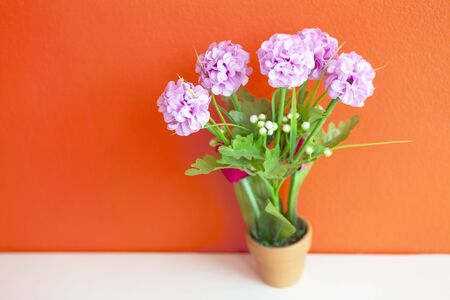 lovely pink artificial hydrangea flower made from cloth on bright orange wall, wallpaper backgroundの写真素材