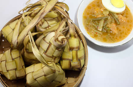 Ketupat is traditional indonesian food, woven coconut leaves filled with rice and eaten with papaya vegetables, , served on Eid al-Fitr or Eid al-Adhaの写真素材