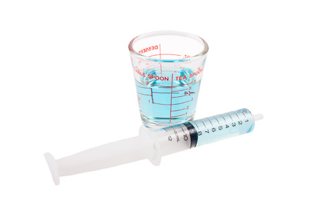 Medical syringe and measuring cup with blue liquid isolated on white backgroundの写真素材