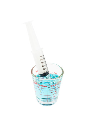 Medical syringe and measuring cup with blue liquid isolated on white backgroundの写真素材