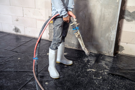 Construction workers holding cement spraying linesの写真素材