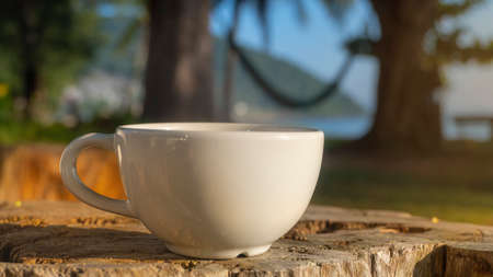 Coffee cup on wood table in morning beachの写真素材