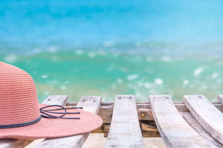 A tourist's pink wide-brimmed hat on a wooden bridge, a beach walkway.の写真素材