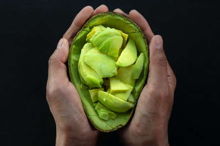 The woman holds the chopped avocado and seasoned it with salt.の写真素材