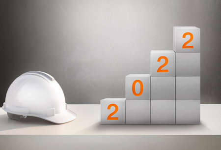 Happy New Year 2022 Construction and Industry.White Helmet and a numbered concrete cube on the desk of an engineer or construction worker.の写真素材