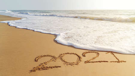 Goodbye, 2021 hello to 2022 happy New Year coming. Handwriting on the beach.の写真素材