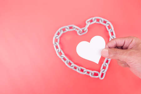 Man hands holding a white heart inside an iron chain, heart health, protective, CSR responsibility, world health day, world mental health day, foster home, wellbeing.の写真素材