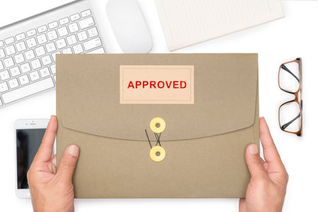 Man's hand holding approved paper folder or important information for work or presentation to the organization.の写真素材
