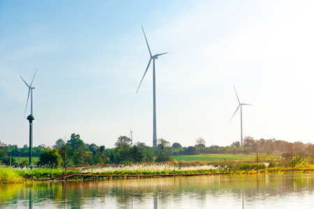 An electric wind turbine is located on top of a mountain. Reflection on the water surface in the swampの写真素材