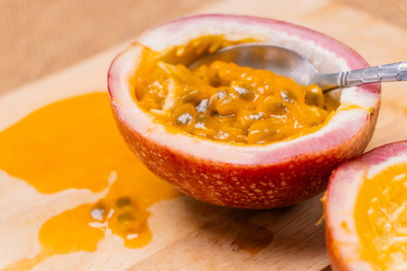 scooping out pulp and seeds from a purple passion fruit with Spoonの写真素材