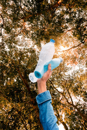 Hands of a tourist or volunteer Collecting trash from plastic water bottles in the forestの写真素材