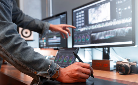 Asian male creator, works with footage or video on his personal computer, in his creative office...