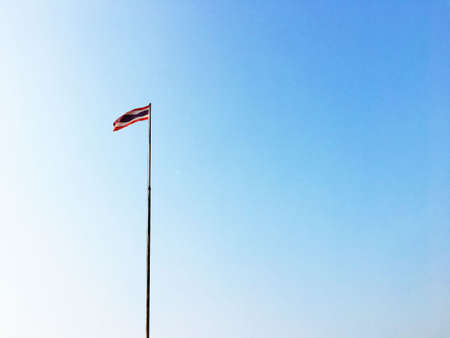 Thai flag is swaying with high pole with blue sky backgroundの写真素材