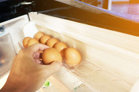 hand of man is taking egg in refrigeratorの写真素材