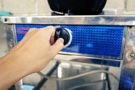 hand of man is reach out for adjust Fire strength level Of gas stove for cook in kitchenの写真素材