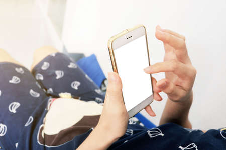 Asian Pregnant woman is sleeping and play smartphone by using finger touch to white blank screen of smartphoneAsian Pregnant woman is sleeping and play smartphone by using finger touch to white blank screen of smartphoneの写真素材