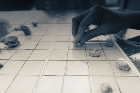 Hand of Asian woman picked the stones to play checkers.の写真素材