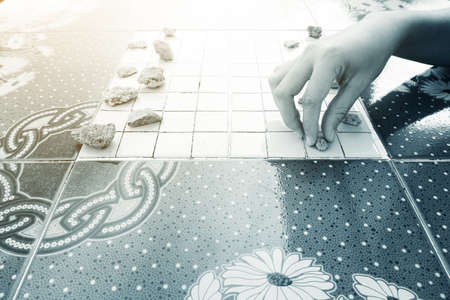 Hand of Asian woman picked the stones to play checkers.