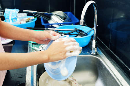 Woman's hand washing dishes fork and spoon with sink.の写真素材