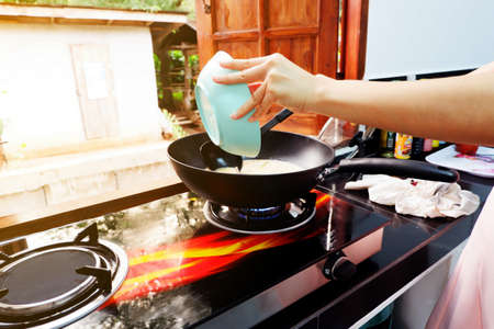 The hand of a woman is cooking with a pan And use a ladle to stir and scoop