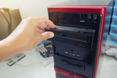 Man's hand inserting CD-ROM into computer caseの写真素材