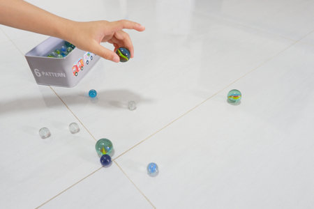 A boy's hand is picking up a marble to play with.の写真素材