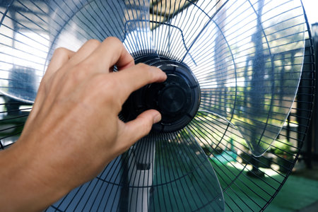 Hands of a technician repairing a fan, replacing capacitors, checking thermal fuses and assembling the fan grille.の写真素材