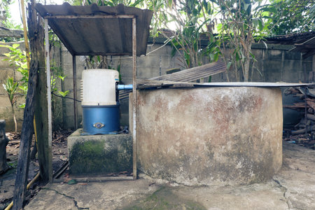 Installing a high-pressure automatic jet water pump with a pair of old wells in rural areas and using old zinc sheets as a roof for the water pump and covering the well mouth.の写真素材