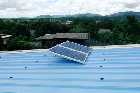 Two large solar panels are installed on a blue metal roof of a rural house using steel legs to...