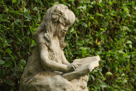 Old statue of a young girl read the book 