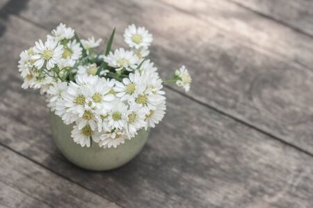 Blossom flower in vase on wood table in vintage color filter stylish. Shallow depth of field. Top view shot.の写真素材