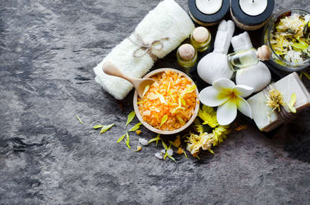 Top view of citrus spa salt with aroma gel, soft yellow towel, massage compress, soap, candle, and dry flower in glass bowl on grunge background, for spa and health care conceptの写真素材