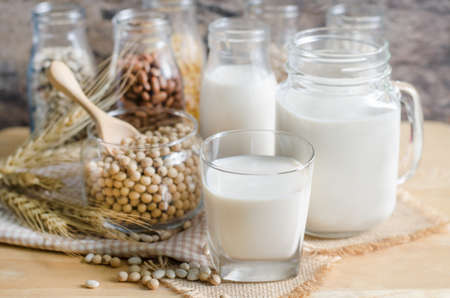 Closed up fresh organic soybean milk in glass bottle with fresh seeds on wooden backgroundの写真素材