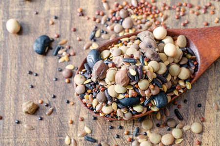 Mixed dry organic cereal and grain seeds in wooden spoon, for clean or healthy food ingredient or...