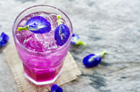 Fresh sweet buttlefly pea juice with ice in glass on grunge wooden backgroundの写真素材