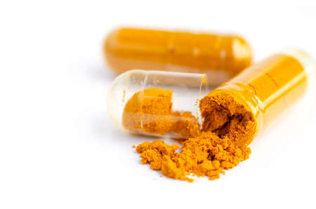 Closed up turmeric powder in plastic capsule on white background, for natural drug or treatment conceptの写真素材