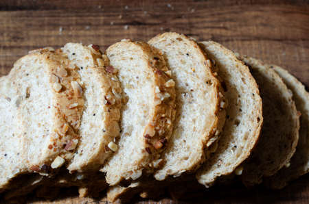 Group of sliced whole wheat bread on wooden background in dark tone ready for breakfast meal