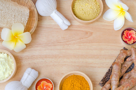 Organic turmeric and thanaka powder with herbal massage compress, aroma candle and spa equipment on wooden background with copy space, for health care and spa treatment conceptの写真素材